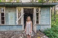 A woman in a dress stands in the background of an old abandoned dilapidated house Royalty Free Stock Photo