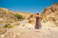 Woman in dress walking back to camera in desert canyon dry sand stone wilderness scenic environment Royalty Free Stock Photo