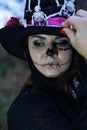 A woman dressed as Baron Saturday poses for the camera. The model is wearing a cylinder hat decorated with skeleton Royalty Free Stock Photo