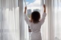 Woman dressed in bathrobe stands near window Royalty Free Stock Photo