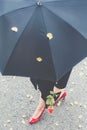 Woman walking in red high heels with a black umbrella Royalty Free Stock Photo