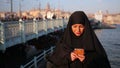 Woman dressed with black headscarf, chador using mobile phone