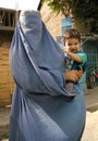 Kabul, Afghanistan: A woman dressed in a blue burqa holding a child