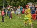 A woman dressed in a clown costume plays with children in the fr