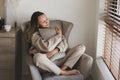 Woman dressed in comfy grey loungewear sitting in a cozy armchair Royalty Free Stock Photo