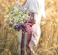 a woman dressed in an embroidered national Ukrainian costume with a bouquet of wild flowers in a wheat field. Ukrainian wheat, Royalty Free Stock Photo