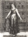 Woman dressed in gypsy costume standing in front of rug