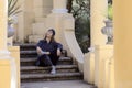 Woman dressed in hip-hop style sits on the steps among the columns in the park Royalty Free Stock Photo