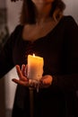 A woman dressed in a medieval dress holds a burning white candle in her hand. Mystery witch Royalty Free Stock Photo