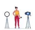Woman dressed in sports clothes does exercises with dumbbells recording video with camera on tripod. Social network blogging,
