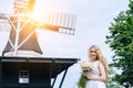 Woman dressed on traditional Dutch dress, wooden shoes yellow clogs klompen holding bouquet of Chamomile flowers with Royalty Free Stock Photo