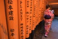 Woman dressed in traditional japanese costume walking under tori gates at the fushimi-inari shrine, Kyoto Japan