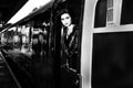 Woman dressed in vintage evening dress leaning out of train window and blowing a kiss