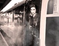 Woman dressed in vintage evening dress leaning out of train window and blowing a kiss