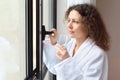 Woman dressed in white bathrobe holds glass