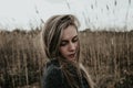 Woman dressed in wool coat looking down over her shoulder. Background bulrush. Outdoor. Medium shot