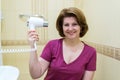 Woman dries hair a hair dryer in a bathroom