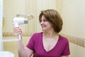 Woman dries hair a hair dryer in a bathroom