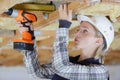 woman drilling wood plank ceiling
