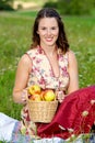 Woman in drindl sitting in a meadow and holding a basket with apples Royalty Free Stock Photo