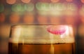 Woman Drinking Beer Concept. Closeup of Glass of Beer with Red Lipstick Mark in Bar. Feminine Mood