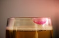 Woman Drinking Beer Concept. Closeup of Glass of Beer with Red Lipstick Mark