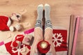 Woman drinking cappuccino coffee and sitting on the wooden floor. Close-up of female legs in warm socks with a deer with christmas Royalty Free Stock Photo