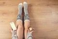 Woman drinking cappuccino coffee and sitting on the wooden floor. Close up of woman`s hands holding cup of coffee and using smart Royalty Free Stock Photo