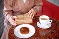 Woman drinking coffee or cappuccino in french cafe on street. hands holding eco wrapped gift box sitting at table in pastry shop Royalty Free Stock Photo