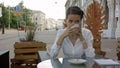 Woman drinking a coffee from a cup in a restaurant terrace while thinking and looking sideways Royalty Free Stock Photo