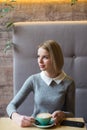 Woman drinking coffee in the morning at restaurant. Soft focus on the eyes. Sellphone on table. Vertical photo. Royalty Free Stock Photo