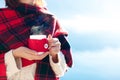 Woman drinking coffee at sea beach. Winter picnic. Girl in red plaid enjoying calm nature Royalty Free Stock Photo