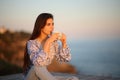 Woman drinking coffee at sunset on the beach Royalty Free Stock Photo