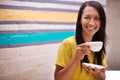 Woman, drinking coffee and smile outdoors, relax and laughing for humor or comedy by wall background. Female person