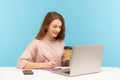 Woman drinking coffee, working on laptop and making notes on paper. Student studying, writing in notebook Royalty Free Stock Photo