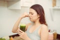 Woman drinking disgusting green smoothie, closing nose, bad smell and taste Royalty Free Stock Photo