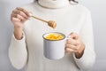 Woman drinking golden turmeric milk with honey over gray