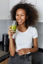 Woman drinking green detox juice, smoothie drink in kitchen Royalty Free Stock Photo