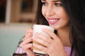 Woman drinking hot cappuccino coffee and eating cake at a cafe. Royalty Free Stock Photo