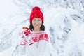 Woman drinking hot chocolate in Christmas morning in snowy garden. Girl in knitted Nordic sweater, hat and mittens holding cup Royalty Free Stock Photo