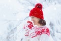 Woman drinking hot chocolate in Christmas morning in snowy garden. Girl in knitted Nordic sweater, hat and mittens holding cup