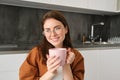 Woman drinking hot coffee at home. Thoughtful young woman drinking a cup of tea while thinking. Pretty girl with sweater Royalty Free Stock Photo