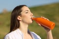 Woman drinking orange juice from a blank bottle