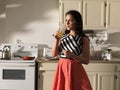 Woman drinking orange juice in kitchen wearing retro dress Royalty Free Stock Photo