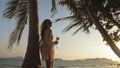 Woman drinking pineapple cocktail Pina Colada near palm tree, in Royalty Free Stock Photo