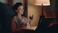 Woman drinking red wine with notebook. Girl looking laptop with wineglass. Royalty Free Stock Photo