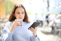 Woman drinking soda in a bar terrace checking phone Royalty Free Stock Photo