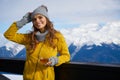 Woman drinking warm tea in the rustick wooden terrace on mountain, alpine view, snow on hills