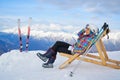 Woman drinking warm tea in the rustick wooden terrace on mountain, alpine view, snow on hills