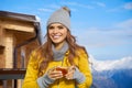 Woman drinking warm tea in the rustick wooden terrace on mountain, alpine view, snow on hills